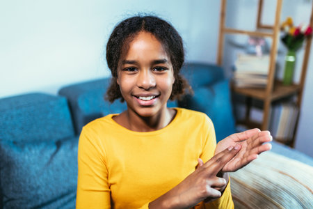 Beautiful smiling black deaf girl using sign language at homeの写真素材