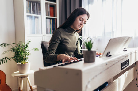 Happy girl is playing piano for her hobby relax time in home living room. Portrait Of Smiling Teenage Girl At Home Playing The Pianoの写真素材