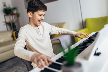 Little boy playing piano in living room. Child having fun with learning to play music instrument at home.の写真素材