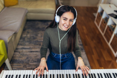 Happy girl is playing piano for her hobby relax time in home living room. Portrait Of Smiling Teenage Girl At Home Playing The Pianoの写真素材