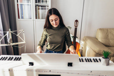 Happy girl is playing piano for her hobby relax time in home living room. Portrait Of Smiling Teenage Girl At Home Playing The Pianoの写真素材