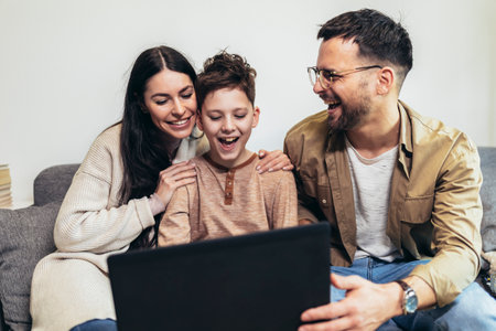Cheerful Caucasian parents and their little boy using laptop at home together, watching movie or browsing internetの写真素材