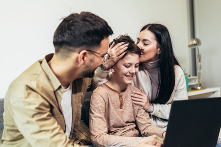 Cheerful Caucasian parents and their little boy using laptop at home together, watching movie or browsing internetの写真素材