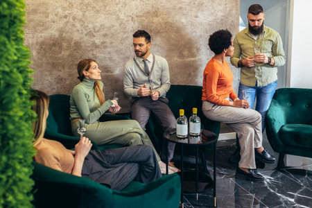 Group of  businesspeople sitting together in a co-working space and celebrating with alcohol drink.の写真素材