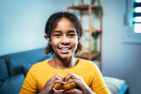 Beautiful smiling black deaf girl using sign language at homeの写真素材