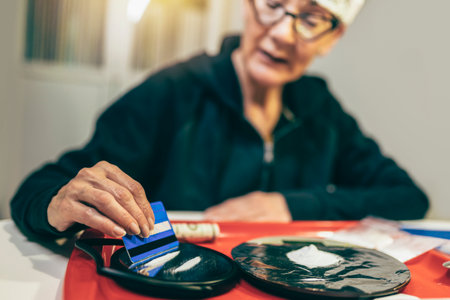 Senior woman drug addict making cocaine line with credit card on glass surface.の写真素材