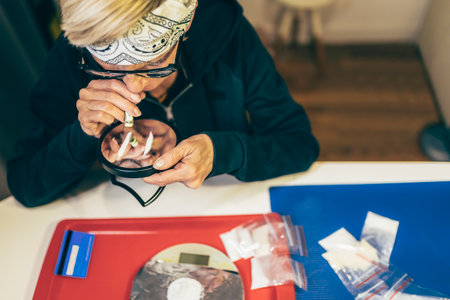 Senior woman sniffs line of cocaine through a rolled 1 dollar bill on  table close-up.の写真素材