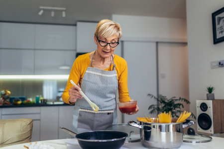 Happy senior woman cooking in her modern kitchenの写真素材