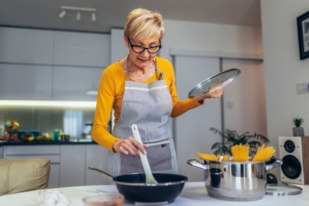 Happy senior woman cooking in her modern kitchenの写真素材