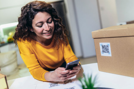 Woman affixing QR codes onto storage boxes. She is focused on her task, carefully placing the QR codes onto each box with precision. Concept organization, efficiency, or technology in storage management.の写真素材