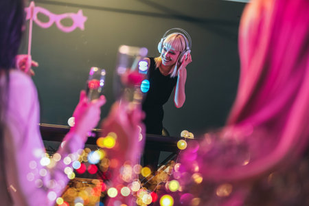 Group of people dancing in the club with DJ in background
