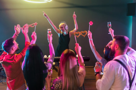 Group of people dancing in the club with DJ in backgroundの写真素材