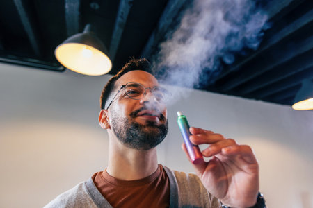Young man smoking an electronic cigarette to quit tobacco. Vape man. Alternative nicotine-free...
