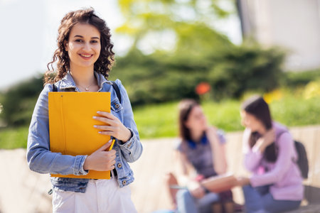 Student standing with her note-book while her friends are studying behind herの写真素材