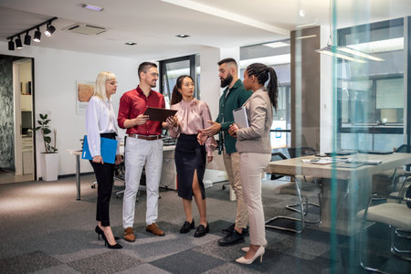 A business team is standing in a modern office and having a discussion. Group of multiethnic business people working together in the officeの写真素材