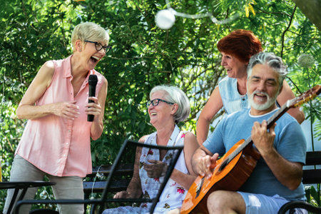 Group of elderly people enjoying their retirement by going on a picnic, playing a guitar and singing, making barbeque, making memories and making their friendship strongerの写真素材