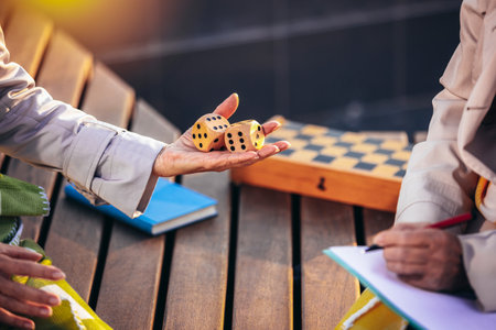 Two older rolling the dice and playing games. They are sitting in thel park in the autumn.の写真素材