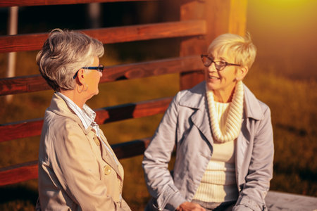 Two older women in the colorful park listen and talk to each other.の写真素材