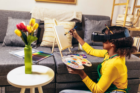 A preteen girl is using a paintbrush to bring creativity and color to life on a table, creating an...