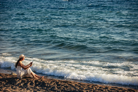 Teenage girl using a digital tablet to take pictures on the beachの写真素材