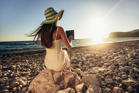 Teenage girl using digital tablet to take pictures on the beachの写真素材