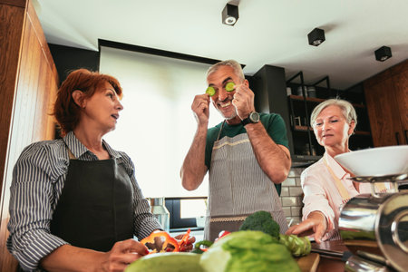 Group of senior friends at dinner party at home, cooking.