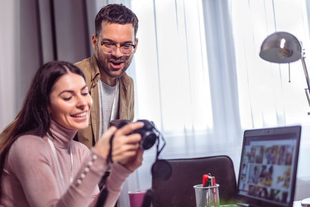 Young couple of photographers working with laptop at the working place with computers in the studioの写真素材