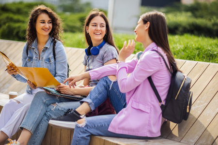 Group of collage girls sitting on bench and studying for schoolの写真素材