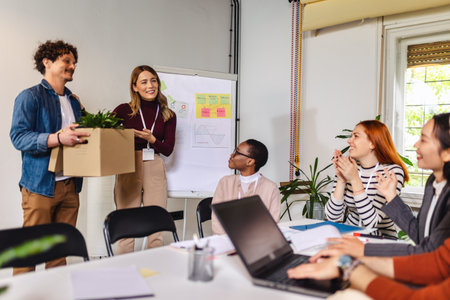 Business team meets a new employee.  New coworker holding a box standing in the modern office with...