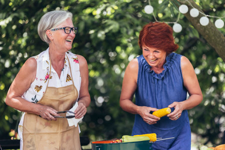 Elderly people are making barbeque, drinking beverages, making memories, and laughing.の写真素材
