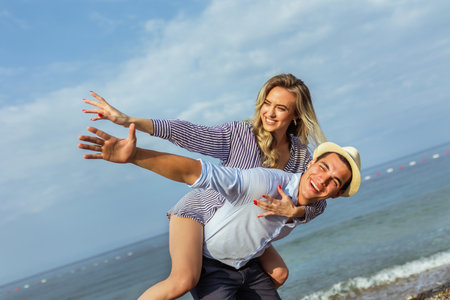 Happy young couple laughing and hugging on the beachの写真素材