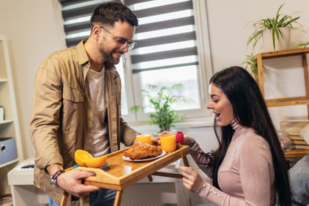 Man holding breakfast tray to a happy relaxed womanの写真素材