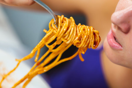 Close-up of girl eating spaghetti bologneseの写真素材