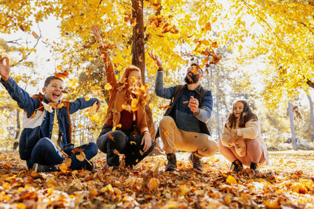 Happy family throwing colorful autumn leaves in the park.の写真素材