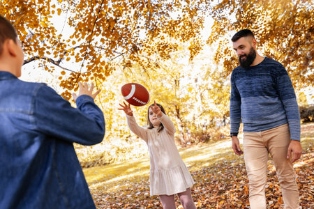Family playing american football in park. Family and kids, nature concept.の写真素材