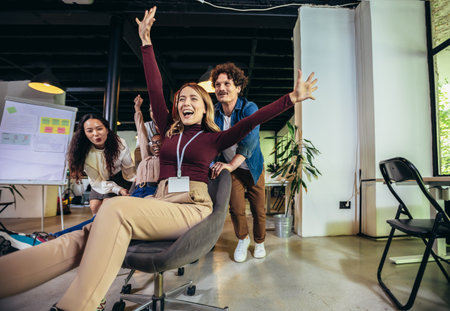 Young cheerful businesspeople in smart casual wear having fun while racing on office chairs and smilingの写真素材