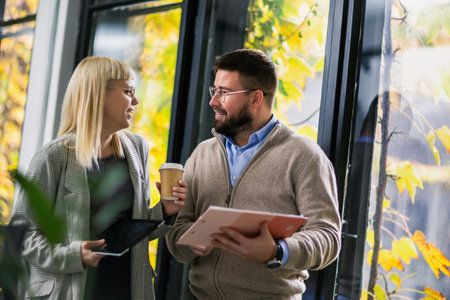 Colleagues standing together holding documents and cup of coffee in modern office.の写真素材