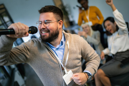 Business people making team training exercise during team building seminar singing karaokeの写真素材