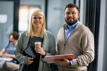 Colleagues standing together holding documents and cup of coffee in modern office.の写真素材