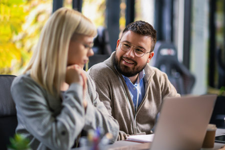 Businessman and businesswoman in meeting using laptop and discussing business strategy. Business...
