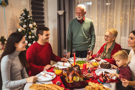 Grandfather is making a toast at the table. Family celebrating Christmas together eating homemade food.の写真素材