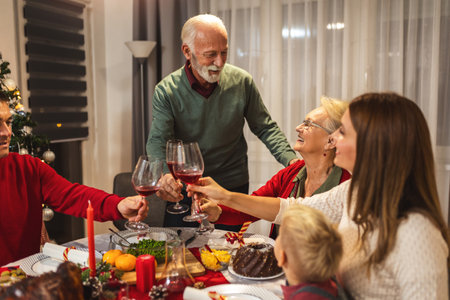 Grandfather is making a toast at the table. Family celebrating Christmas together eating homemade food.の写真素材