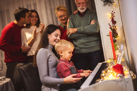 Granddaughter and grandson playing a piano for their family on Christmas Eve.の写真素材