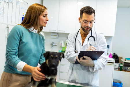 Young man, a veterinarian by profession, examines a dog in modern vet clinic.Young owner helps to calm down the pet and talks with the vet specialist.の写真素材
