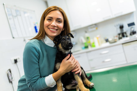 Young woman holding her cute dog on hands in lounge of veterinary hospitalの写真素材