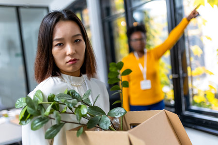 Business woman carrying packing up all her personal belongings and files into a brown cardboard box to resignation in modern office, resign concept.の写真素材
