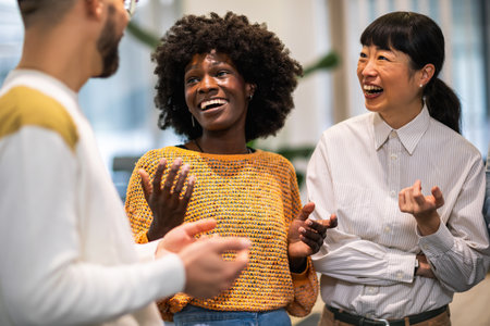 Multiethnic colleagues standing together and talking about work in their modern office.の写真素材