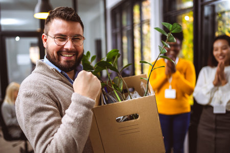 Business team meets a new employee.  New coworker holding a box standing in the modern office with other colleaguesの写真素材