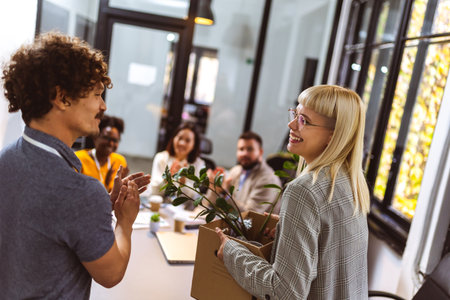 Business team meets a new employee.  New coworker holding a box standing in the modern office with...
