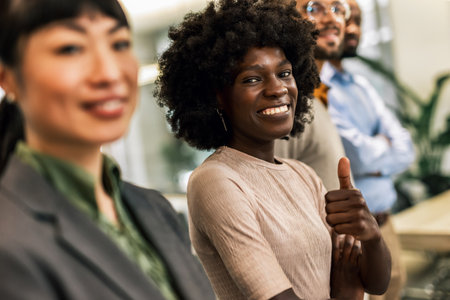 Young African American woman standing in the office holding thumbs upの写真素材